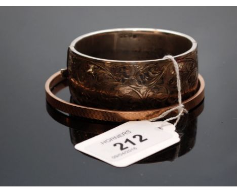 A SILVER BANGLE OF SCROLLED FOLIATE DESIGN, BIRMINGHAM ASSAY ALONG WITH A 9CT GOLD BANGLE 