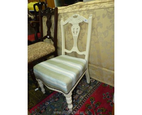 A cream painted framed Edwardian nursing Chair with striped upholstery and cushion.