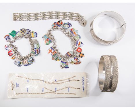 A collection of silver jewellery to include two silver bangles, two silver and enamel charm bracelets with city shields and a