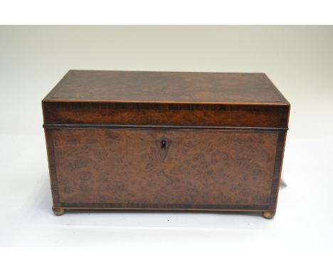 A George III amboyna tea caddy, crossbanded and string, triple division interior, brass side handles, brass ball feet