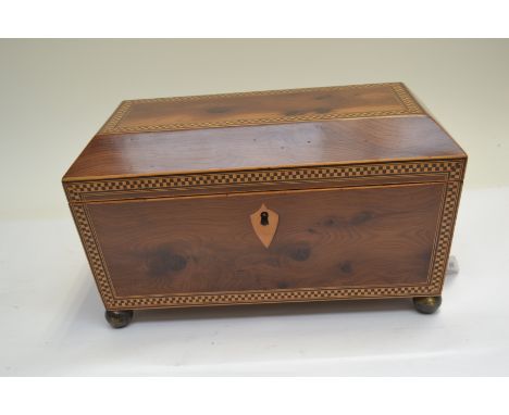 A Regency yew wood tea caddy of sarcophagus form, parquetry inlaid, triple division interior, side ring handles, brass ball f