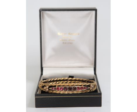 An 9ct gold red stone set bangle, with diamond accents, internal diameter approx 55mm, total gross weight approx 8.3gms&nbsp;