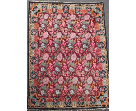 A large Kelim carpet, with polychrome floral field on a puce ground, 11ft 2in by 8ft 1in.