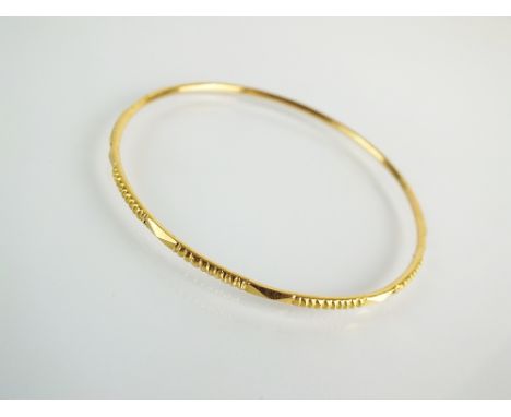 A yellow metal bangle, with ribbed decoration, stamped '21c', weight 9.4gms