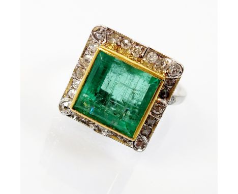 An emerald and diamond cluster ring, designed as a large central square cut emerald measuring approx 11mm x 11mm, collet set 