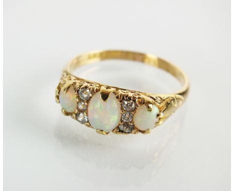 An Edwardian nine stone opal and diamond ring, designed as three graduated oval cabochon opals interspersed with six old cut 