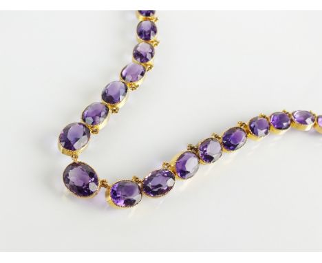 A late 19th century amethyst riviere necklace, designed as thirty-five oval mixed cut amethysts milgrain set in yellow metal,