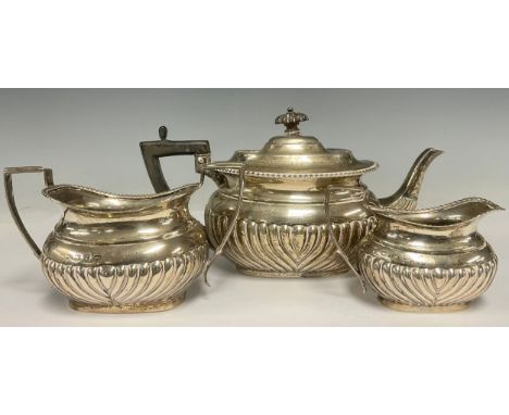 A late Victorian silver composed half fluted three-piece tea service, the teapot, London 1898, the cream jug and sugar basin,