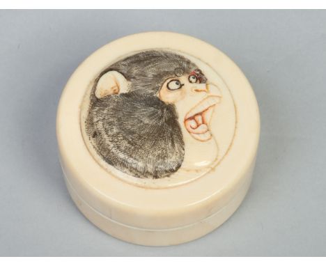 A Japanese Meiji period circular ivory snuff box and cover. Carved and stained with the head of a monkey, 6.5cm diameter.    
