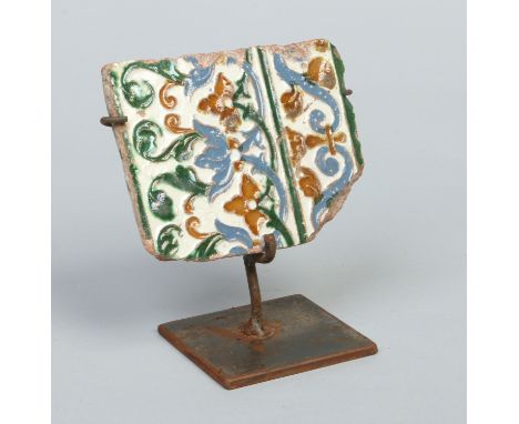 An 18th / 19th century Ottoman tile fragment on metal stand. Tube lined and decorated in coloured glazes, 14cm wide. 