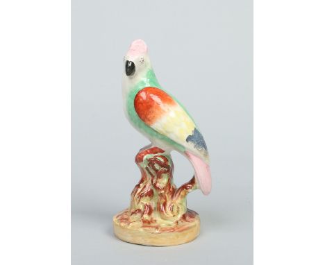A Victorian Staffordshire pottery model of a parrot. Decorated in coloured enamels and raised on a circular naturalistic base
