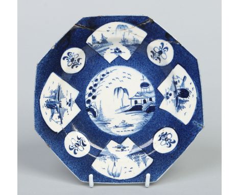 A Bow octagonal powder blue ground plate. With shaped reserves painted in underglaze blue with landscapes and sprigs. Pseudo 