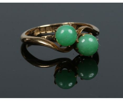 An 18 carat gold crossover ring with a pair of claw set jade studs. Assayed Birmingham 1939, size P.   Condition Report. To b