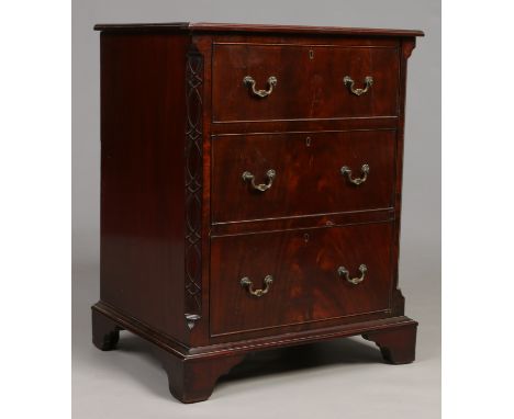 An Edwardian mahogany three drawer chest. With canted corners ornamented with blind fret carving and raised on bracket suppor