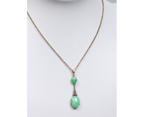 A yellow and white metal drop pendant set with an ovoid and tear drop jadeite tablet, supported on a chain. Pendant 4.75cm.  