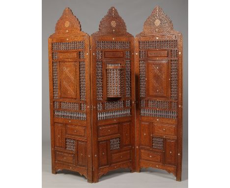 A Moroccan three fold Mashrabiya panelled screen, the central panel with a turret, with carved arched pediments and inlaid wi