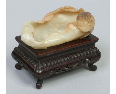 A 19th century Chinese celadon jade brush washer of carved water lily leaf form. With a single flower head and raised on a ha