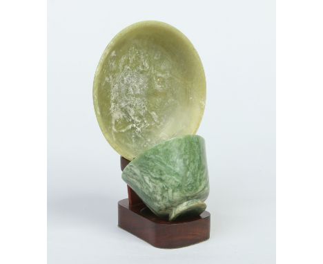 A Chinese 19th century turned jade tea bowl and saucer raised on a hardwood stand. Saucer 14cm diameter.   Condition Report. 