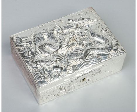 A Japanese silver plated cigarette box. Decorated in relief to the hinged cover with a dragon clutching a flaming pearl, 17cm