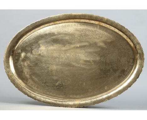An Indian brass scalloped oval serving tray. Engraved with a hunting scene. Inscribed verso; School of Art, Jeypore, 64cm wid