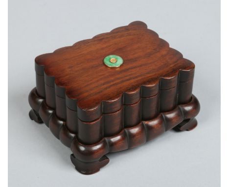 A Chinese carved fluted hardwood rectangular box, cover and stand raised on bracket feet. Set to the cover with a roundel gol