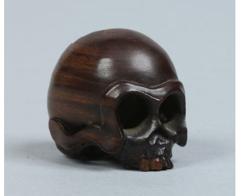 A Japanese carved fruitwood netsuke in the form of a skull. Signed.   Condition Report. To be used as a guide only.  Good con