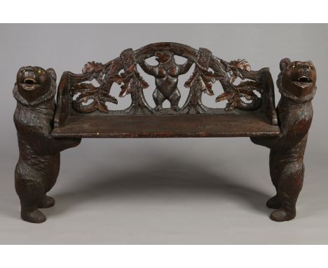 A late 19th century Black Forest carved walnut bench. With bear supports each with glass inset eyes and painted detail. The o