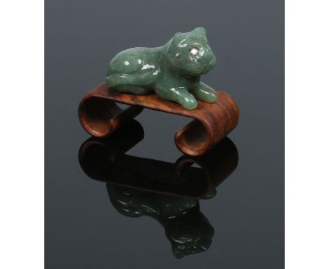 An Indian carved jade model of a recumbent wild cat, with diamond inset eyes and raised on a hardwood scrolling plinth, 5cm n