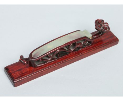 A Chinese carved fruitwood and celadon jade scroll weight formed as a ruyi sceptre raised on a stepped plinth, 23cm wide.   C