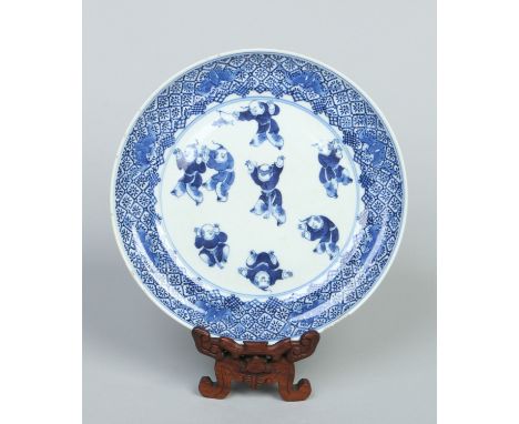 An 18th century Chinese plate of ogee form on hardwood stand. Painted in underglaze blue with a trellis and butterfly border 