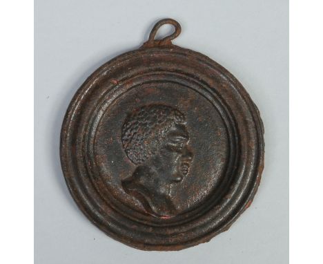 A 19th century cast iron medallion. Decorated with a profile portrait of a Negro in moulded frame and having remnants of enam