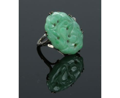 A 9 carat white gold ring set with an oval pierced jade tablet carved with a bird and flowers. Size L.   Condition Report. To