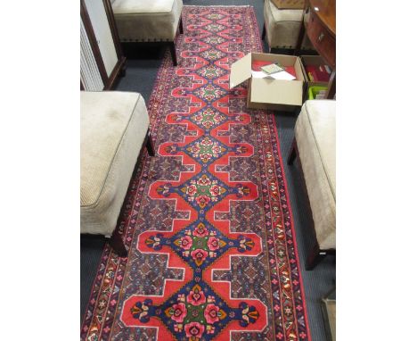 A red and blue ground carpet runner with repeating geometric design, 13ft x 3ft  