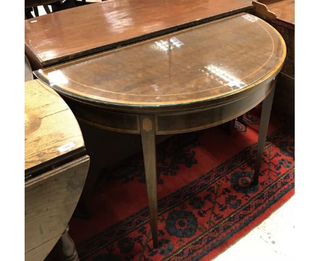 A circa 1900 mahogany and cross-banded Sheraton revival fold-over card table of demi-lune form on square tapered supports