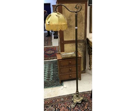 An early 20th Century brass standard lamp with tasselled shade on a tripod base with lion's paw feet