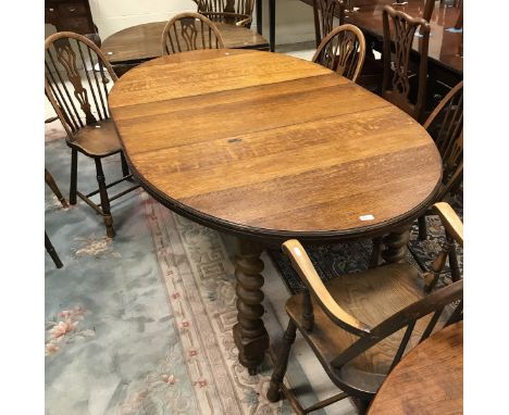 An early 20th Century oak oval draw-leaf dining table on barley-twist supports, together with a set of five stick-back dining