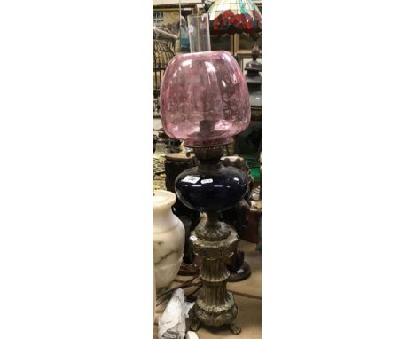 A late Victorian brass oil lamp in the Classical style with blue glass reservoir and cranberry glass shade, together with a p