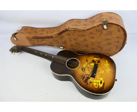 A vintage Roy Rogers 'Singing Cowboy' guitar decorated with image of Roy Rogers playing guitar sat beside a campfire with Tri