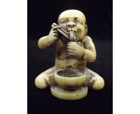 Ivory netsuke in the form of a man eating noodles from a bowl, height 3.5cm