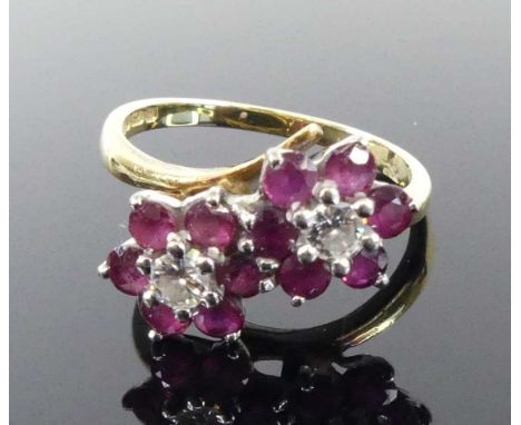 An 18ct yellow and white gold, ruby and diamond crossover style double cluster ring, featuring two round brilliant cut diamon
