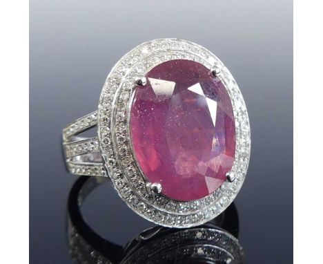 A white metal ruby and diamond oval cluster ring, featuring a centre oval ruby within a border of 40 and 48 round brilliant c