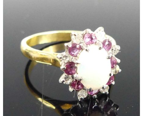 An 18ct gold opal, ruby and diamond flower head cluster ring, the centre cabochon opal measuring 8.1 x 6.3mm, in a surround o
