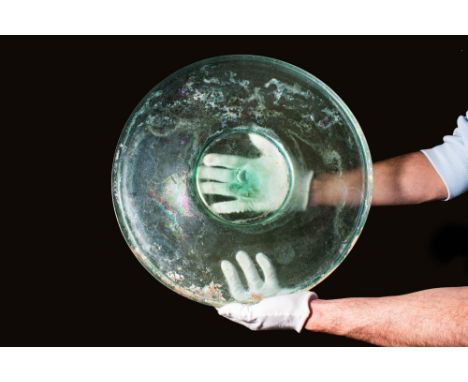 Ca. AD 1 - 200.A translucent green glass plate with a broad shallow form, resting on an elevated concave foot.Size: 420mm x 4