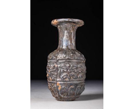 Ca. AD 1 - 300.A moulded glass flask with an oval body and a cylindrical neck that culminates in a thick, outfolded rim. The 