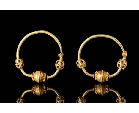 Ca. AD 700 - 900.A stunning pair of impressive gold hoop earrings. Each earring features a carinated sphere pendant in the ce