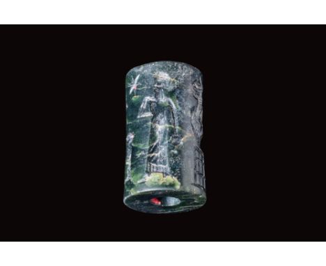 Ca. 800 - 600 BC.A Neo Assyrian black stone cylinder seal. The seal has depicts a standing god in a long robe facing two stan