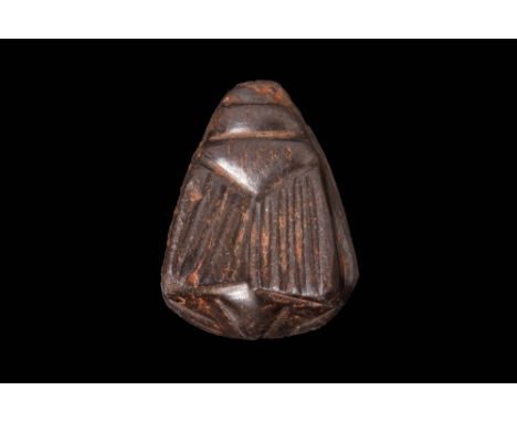 Late Period, Ca. 664 - 332 BC.An amulet carved in black stone in the form of a fly/scarab with detailed wings on top. The ver