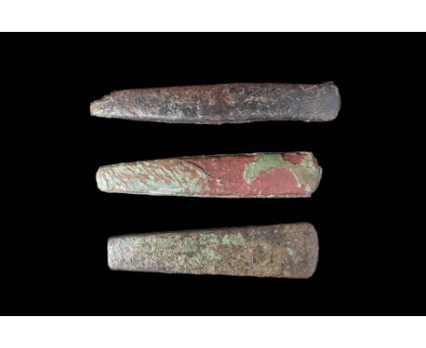 Ca. 3000 - 2000 BC.A collection of three utilitarian bronze axe heads. The axe heads have a broad, trapezoidal blade and a fl