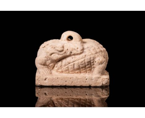 Ptolemaic Period, Ca. 332 - 30 BC.A cream faience amulet in the form of a crocodile turned upon itself, resting on a plinth, 