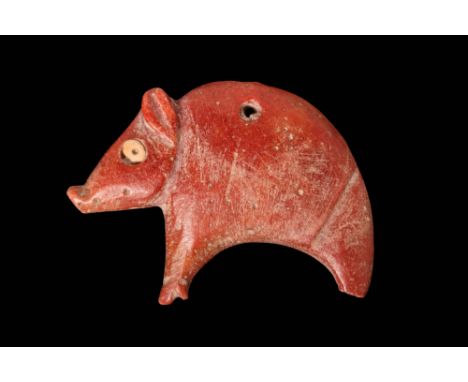 Ca. 3000 - 2500 BC.A red stone amulet of a standing pig. It is depicted with an arched back and it's head down. The head is d